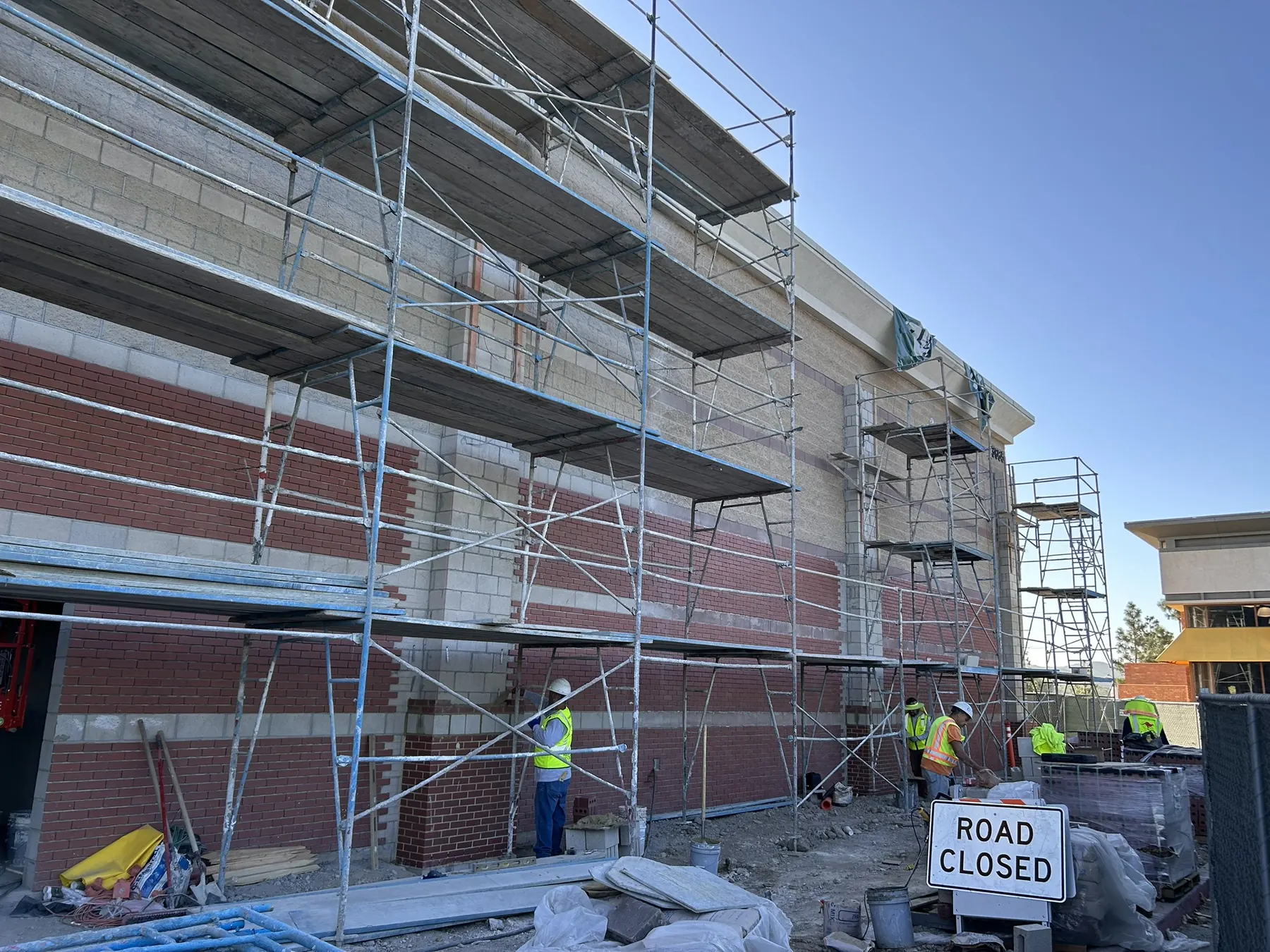 Masonry crew on scaffolding installing banded brick and concrete block on a commercial building