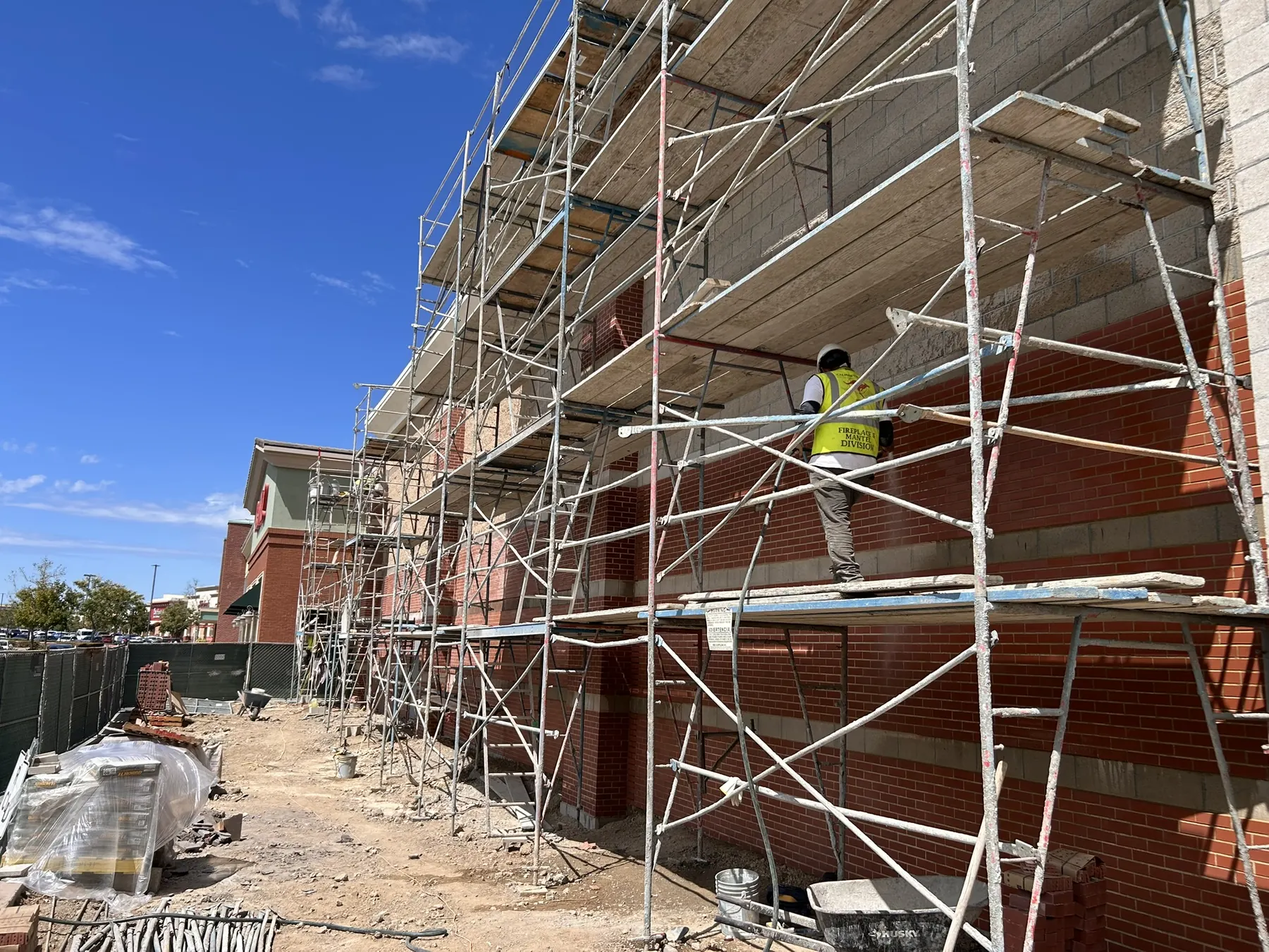 Masonry Division crew member on scaffolding installing brick veneer banding on a commercial building
