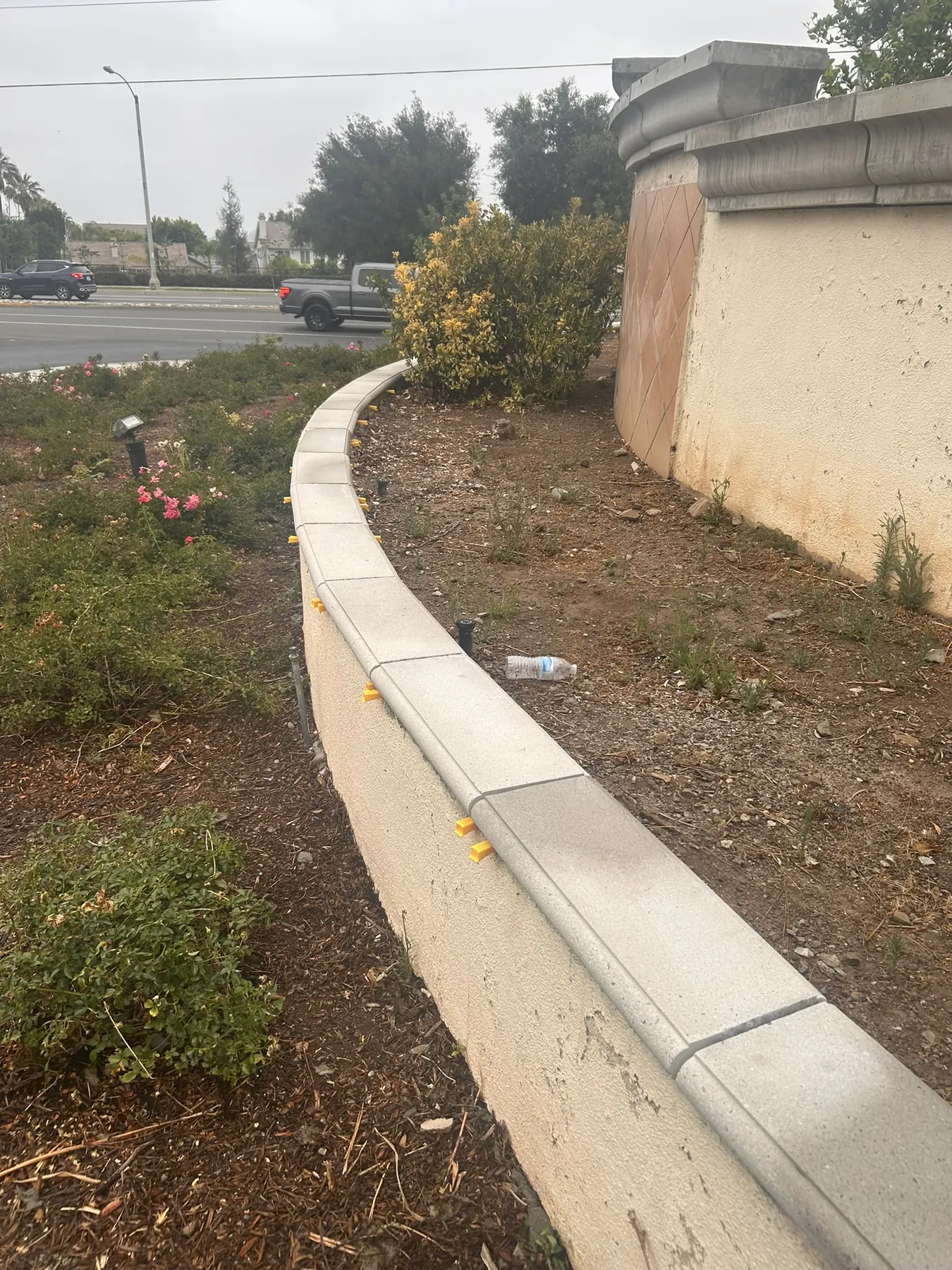 Cast stone coping cap installed along a curved landscaped retaining wall