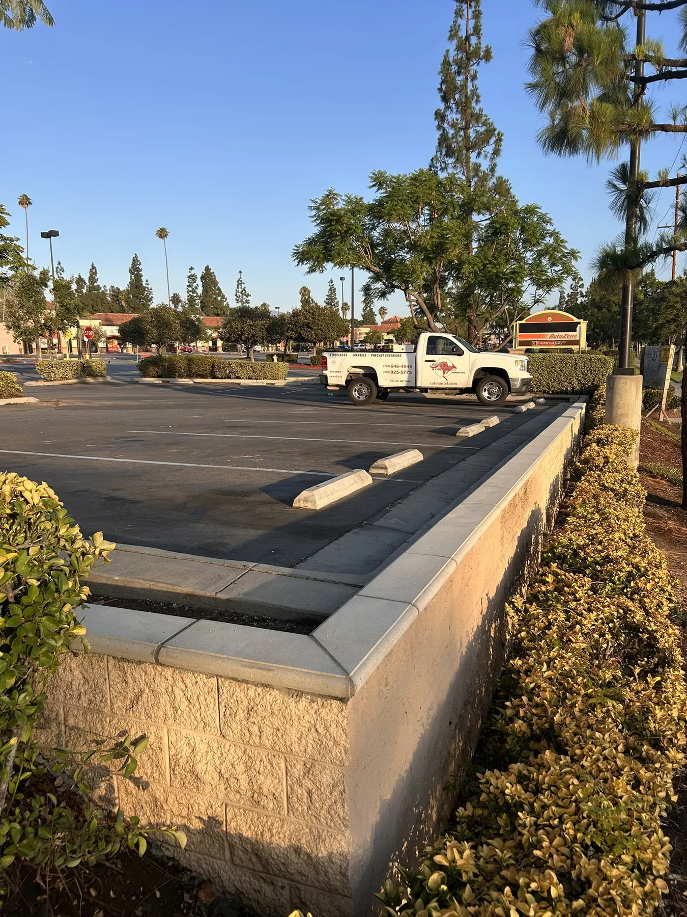 Concrete block wall with precast cap coping bordering a commercial parking lot