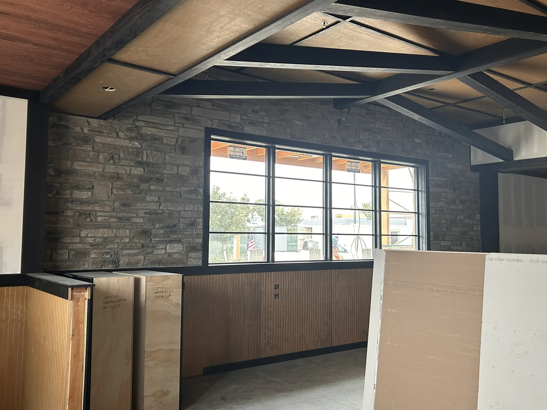 Stacked stone accent wall inside a commercial build-out with exposed wood beam ceiling