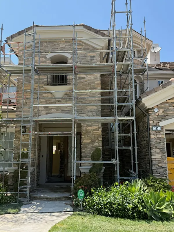 Nearly complete natural stone veneer facade on a custom two-story home with scaffolding still in place
