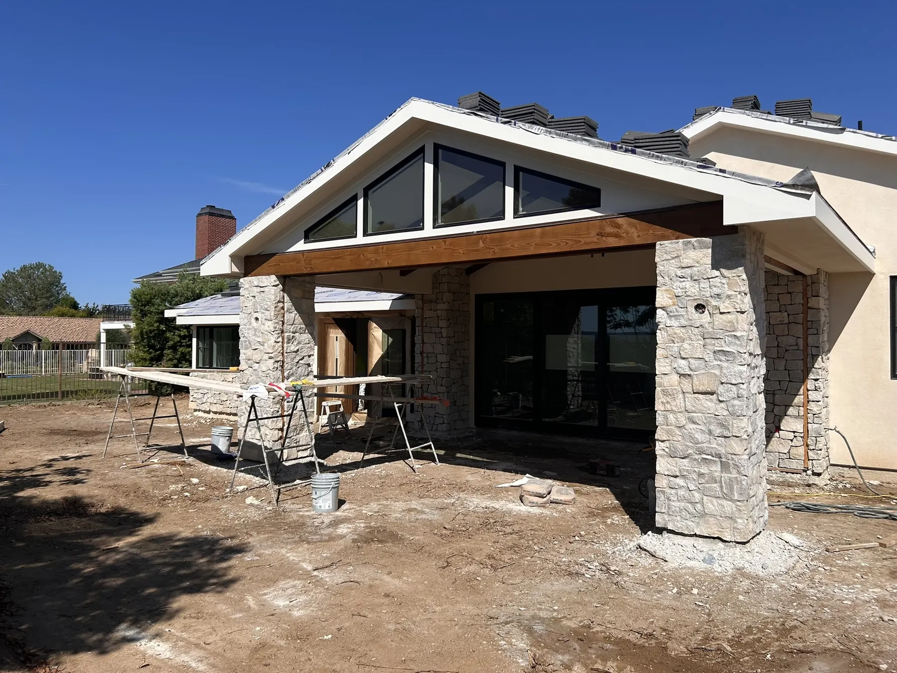 Natural stone veneer columns and a wood beam covered patio on a modern home exterior
