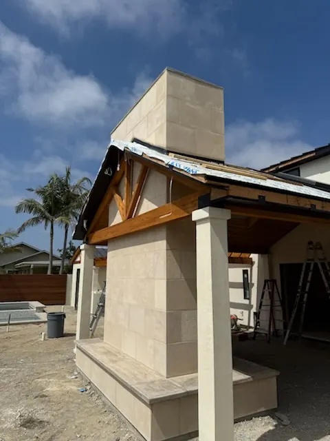 Stone veneer chimney and covered patio corner of a Southern California home under construction